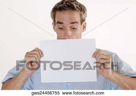 Close-up of a young man holding a blank placard in front of his mouth View Large Photo Image Stock Photography - Close-up of a young man holding a blank placard in front of his mouth. Fotosearch
