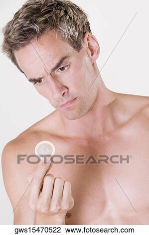 Stock Image - Close-up of a young man holding a condom. Fotosearch
