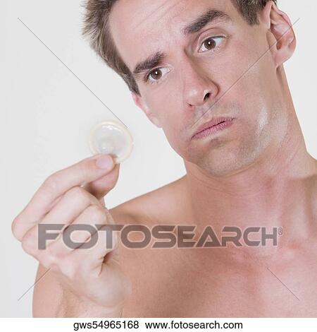 Close-up of a young man holding a condom View Large Photo Image Stock Photo - Close-up of a young man holding a condom. Fotosearch
