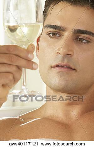 Close-up of a young man holding a glass of white wine in a bathtub View Large Photo Image Stock Image - Close-up of a young man holding a glass of white wine in a bathtub. Fotosearch