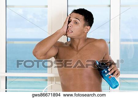 Close-up of a young man holding a bottle of water View Large Photo Image Picture - Close-up of a young man holding a bottle of water. Fotosearch