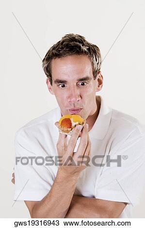 Stock Image - Close-up of a young man holding a strawberry tart. Fotosearch