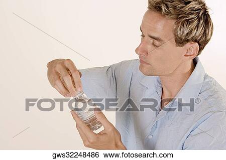 Close-up of a young man holding a water bottle View Large Photo Image Stock Photograph - Close-up of a young man holding a water bottle. Fotosearch