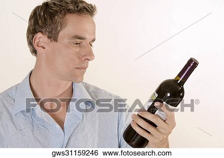 Close-up of a young man holding a wine bottle View Large Photo Image Stock Photograph - Close-up of a young man holding a wine bottle. Fotosearch