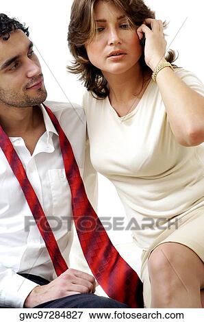 Close-up of a young man looking at a young woman talking on a mobile phone View Large Photo Image Stock Photo - Close-up of a young man looking at a young woman talking on a mobile phone. Fotosearch