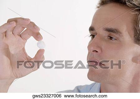 Stock Photograph - Close-up of a young man looking at a cotton ball. Fotosearch