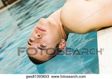 Stock Image - Close-up of a young man lying at the poolside. Fotosearch