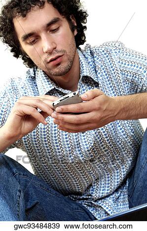Stock Photo - Close-up of a young man operating a personal data assistant. Fotosearch