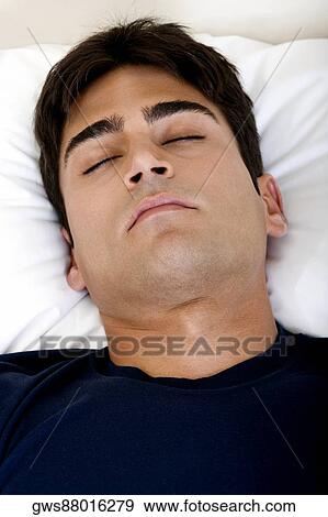 Close-up of a young man sleeping on a bed View Large Photo Image Stock Photo - Close-up of a young man sleeping on a bed. Fotosearch