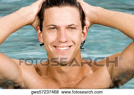 Close-up of a young man smiling with his hands behind his head in a swimming pool View Large Photo Image Stock Photo - Close-up of a young man smiling with his hands behind his head in a swimming pool. Fotosearch