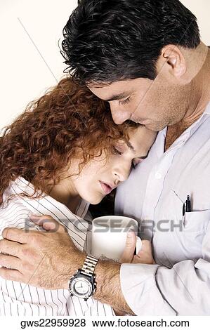 Close-up of a young woman and a mid adult man embracing View Large Photo Image Stock Photo - Close-up of a young woman and a mid adult man embracing. Fotosearch