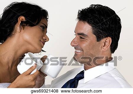 Stock Photo - Close-up of a young woman and a mid adult man holding coffee cups. Fotosearch