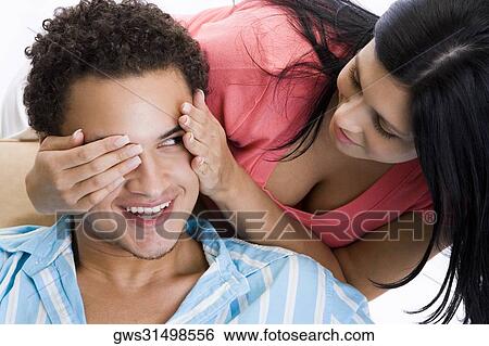 Close-up of a young woman covering a young man's eyes View Large Photo Image Stock Photograph - Close-up of a young woman covering a young man's eyes. Fotosearch