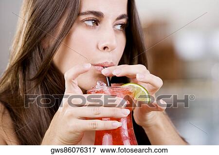 Close-up of a young woman drinking a cocktail View Large Photo Image Stock Photo - Close-up of a young woman drinking a cocktail. Fotosearch