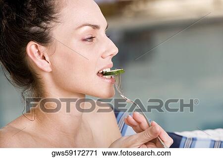 Close-up of a young woman eating a cucumber slice View Large Photo Image Stock Image - Close-up of a young woman eating a cucumber slice. Fotosearch
