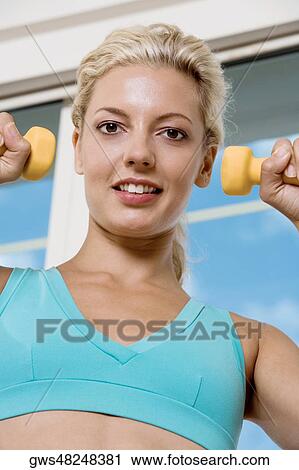 Close-up of a young woman exercising with dumbbells View Large Photo Image Stock Image - Close-up of a young woman exercising with dumbbells. Fotosearch