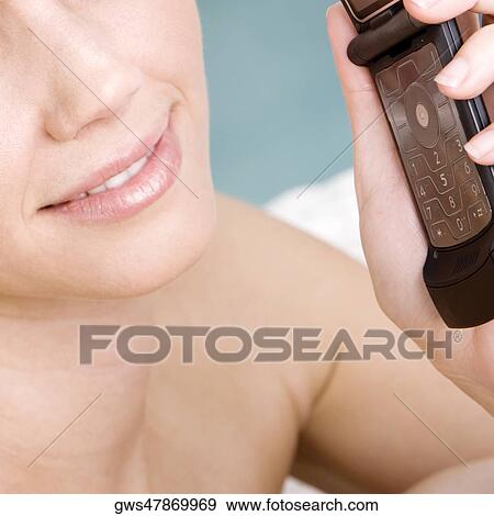 Close-up of a young woman holding a mobile phone View Large Photo Image Stock Photo - Close-up of a young woman holding a mobile phone. Fotosearch