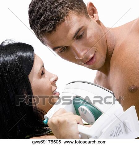 Close-up of a young woman holding an iron in front of a young man View Large Photo Image Stock Photography - Close-up of a young woman holding an iron in front of a young man. Fotosearch