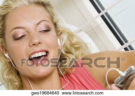 Close-up of a young woman listening to an MP3 player View Large Photo Image Stock Image - Close-up of a young woman listening to an MP3 player. Fotosearch