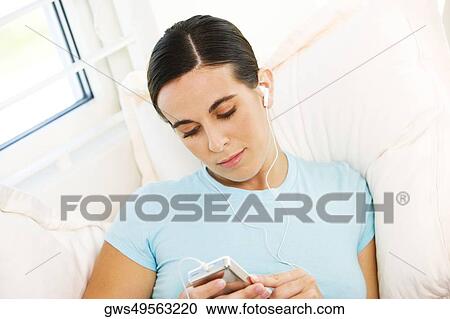 Close-up of a young woman listening to an MP3 player View Large Photo Image Stock Image - Close-up of a young woman listening to an MP3 player. Fotosearch