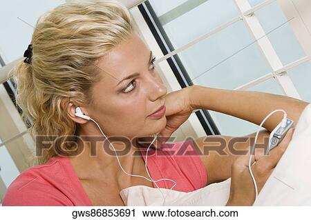 Close-up of a young woman listening to an MP3 player View Large Photo Image Stock Image - Close-up of a young woman listening to an MP3 player. Fotosearch