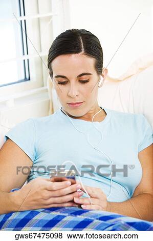 Close-up of a young woman listening to an MP3 player View Large Photo Image Stock Photo - Close-up of a young woman listening to an MP3 player. Fotosearch