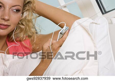 Close-up of a young woman listening to an MP3 player View Large Photo Image Stock Photo - Close-up of a young woman listening to an MP3 player. Fotosearch