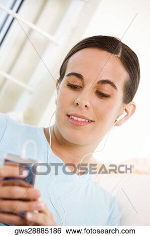Stock Photograph - Close-up of a young woman listening to an MP3 player. Fotosearch
