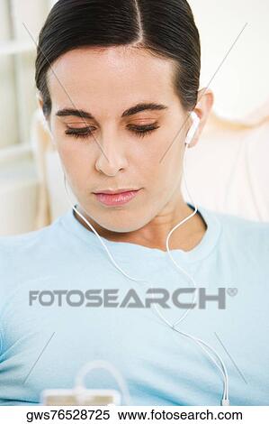 Stock Photography - Close-up of a young woman listening to an MP3 player. Fotosearch