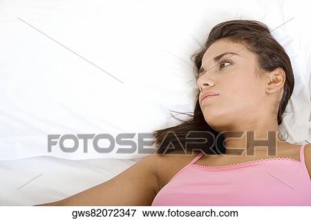 Close-up of a young woman lying down on a bed View Large Photo Image Stock Photo - Close-up of a young woman lying down on a bed. Fotosearch