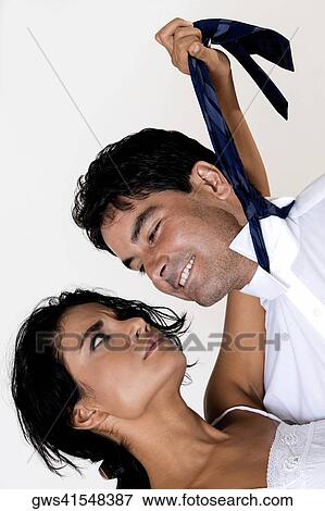 Stock Photo - Close-up of a young woman pulling the tie of a mid adult man. Fotosearch