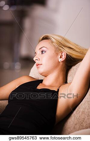 Stock Image - Close-up of a young woman reclining on an armchair. Fotosearch