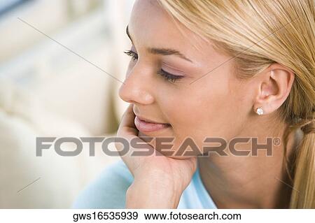 Close-up of a young woman sitting with her hand on her chin View Large Photo Image Stock Photo - Close-up of a young woman sitting with her hand on her chin. Fotosearch