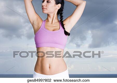 Close-up of a young woman standing with her arms raised View Large Photo Image Stock Image - Close-up of a young woman standing with her arms raised. Fotosearch