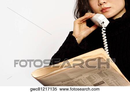 Close-up of a young woman talking on the telephone holding a newspaper View Large Photo Image Stock Photography - Close-up of a young woman talking on the telephone holding a newspaper. Fotosearch