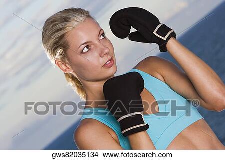 Close-up of a young woman wearing boxing gloves View Large Photo Image Picture - Close-up of a young woman wearing boxing gloves. Fotosearch