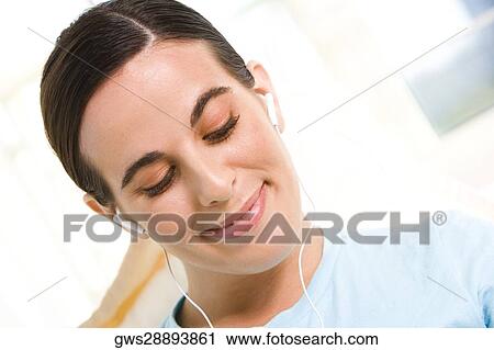 Close-up of a young woman wearing headphones listening to music View Large Photo Image Stock Image - Close-up of a young woman wearing headphones listening to music. Fotosearch
