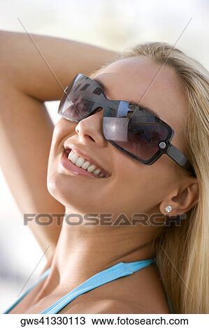 Close-up of a young woman wearing sunglasses View Large Photo Image Stock Image - Close-up of a young woman wearing sunglasses. Fotosearch