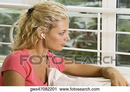 Stock Image - Close-up of a young woman wearing headphones listening to music. Fotosearch
