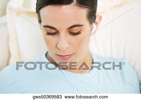 Stock Image - Close-up of a young woman wearing headphones listening to music. Fotosearch