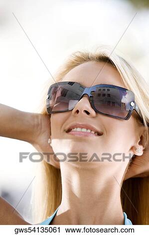 Close-up of a young woman wearing sunglasses View Large Photo Image Stock Image - Close-up of a young woman wearing sunglasses. Fotosearch