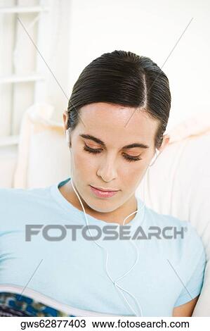 Close-up of a young woman wearing headphones listening to music View Large Photo Image Stock Image - Close-up of a young woman wearing headphones listening to music. Fotosearch
