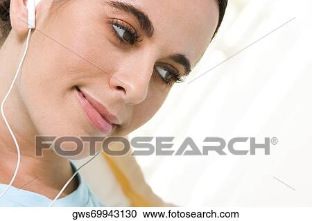 Close-up of a young woman wearing headphones listening to music View Large Photo Image Stock Image - Close-up of a young woman wearing headphones listening to music. Fotosearch