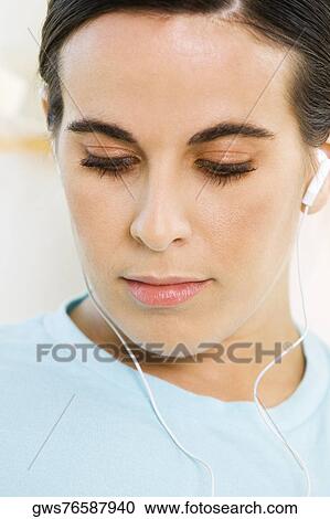 Close-up of a young woman wearing headphones listening to music View Large Photo Image Stock Image - Close-up of a young woman wearing headphones listening to music. Fotosearch