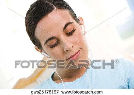 Close-up of a young woman wearing headphones listening to music View Large Photo Image Stock Photo - Close-up of a young woman wearing headphones listening to music. Fotosearch