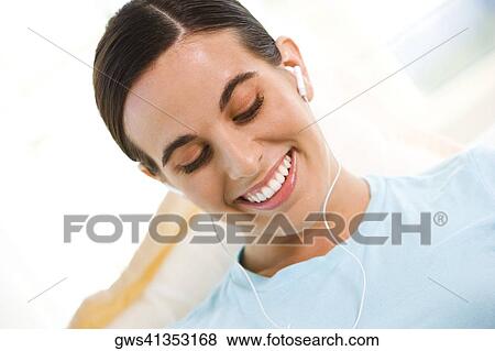 Close-up of a young woman wearing headphones listening to music View Large Photo Image Stock Photo - Close-up of a young woman wearing headphones listening to music. Fotosearch
