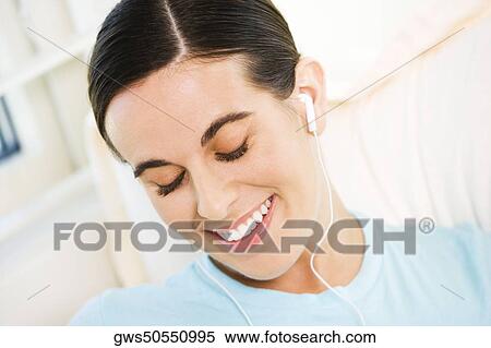 Close-up of a young woman wearing headphones listening to music View Large Photo Image Stock Photography - Close-up of a young woman wearing headphones listening to music. Fotosearch