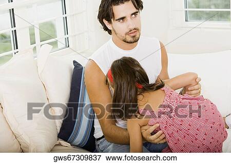 Father and his daughter sitting on a couch View Large Photo Image Stock Photo - Father and his daughter sitting on a couch. Fotosearch