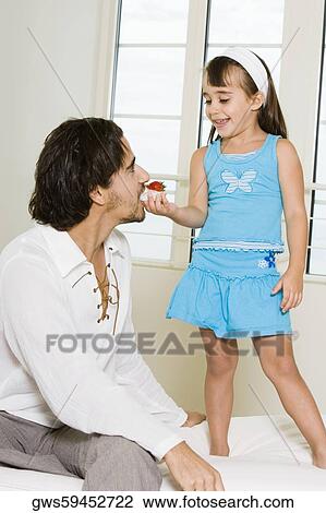 Girl feeding her father a tart View Large Photo Image Stock Image - Girl feeding her father a tart. Fotosearch