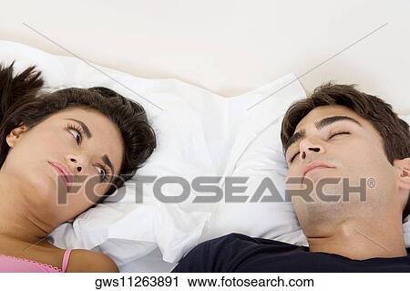 High angle view of a young couple lying on the bed View Large Photo Image Stock Image - High angle view of a young couple lying on the bed. Fotosearch
